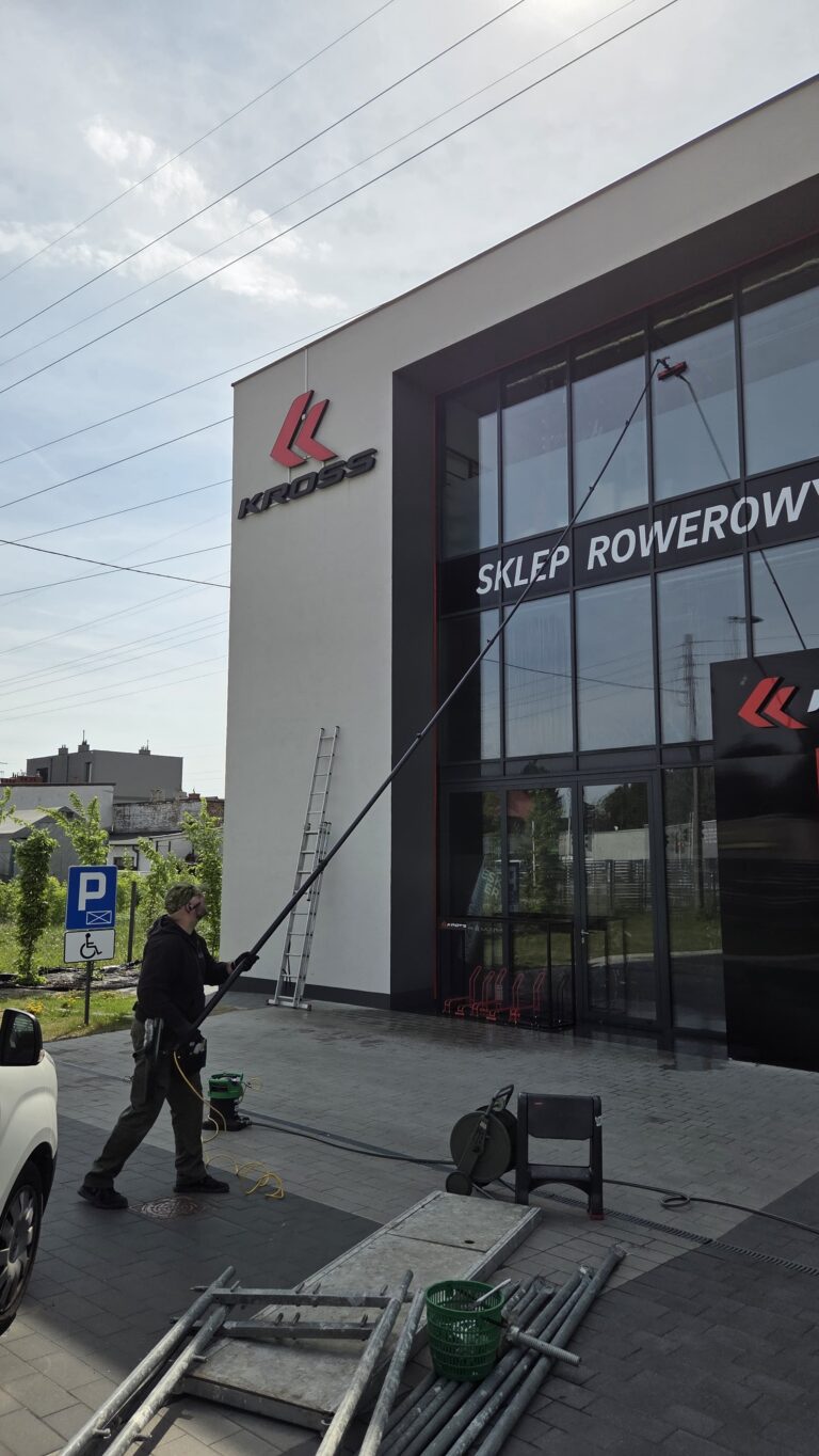 Pracownik R.M.K Cleaning Service podczas czyszczenia elewacji i przeszkleń salonu KROSS w Warszawie.